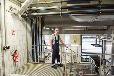Azubi zum Elektroniker für Betriebstechnik steht in technischer Anlage an einer Treppe
