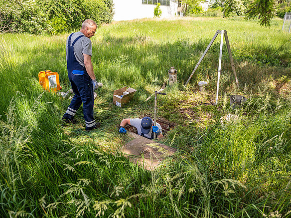 SWM Mitarbeiter aus dem Bereich Wasser Zwei SWM Mitarbeiter aus dem Bereich Wasser steigen in einen Schacht zum Wechsel eines Großwasserzählers