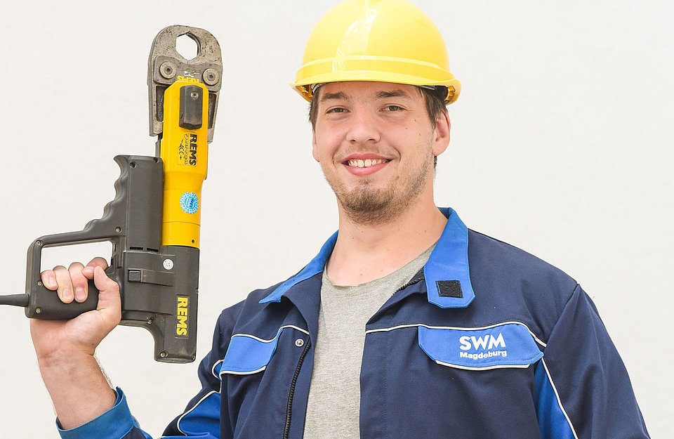 Azubi zum Anlagenmechaniker bei SWM mit Arbeitsgerät in der Hand