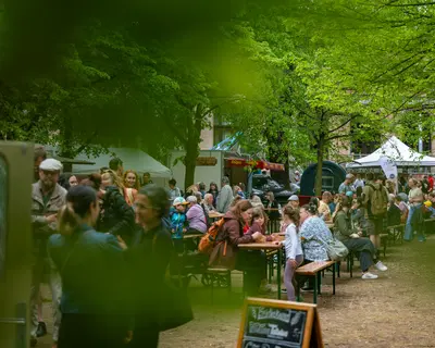 Besucher der Grünen Messe sitzen auf Bänken