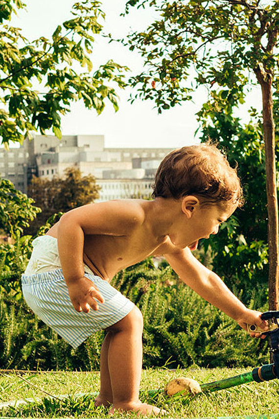 Kind spielt mit Rasensprenger