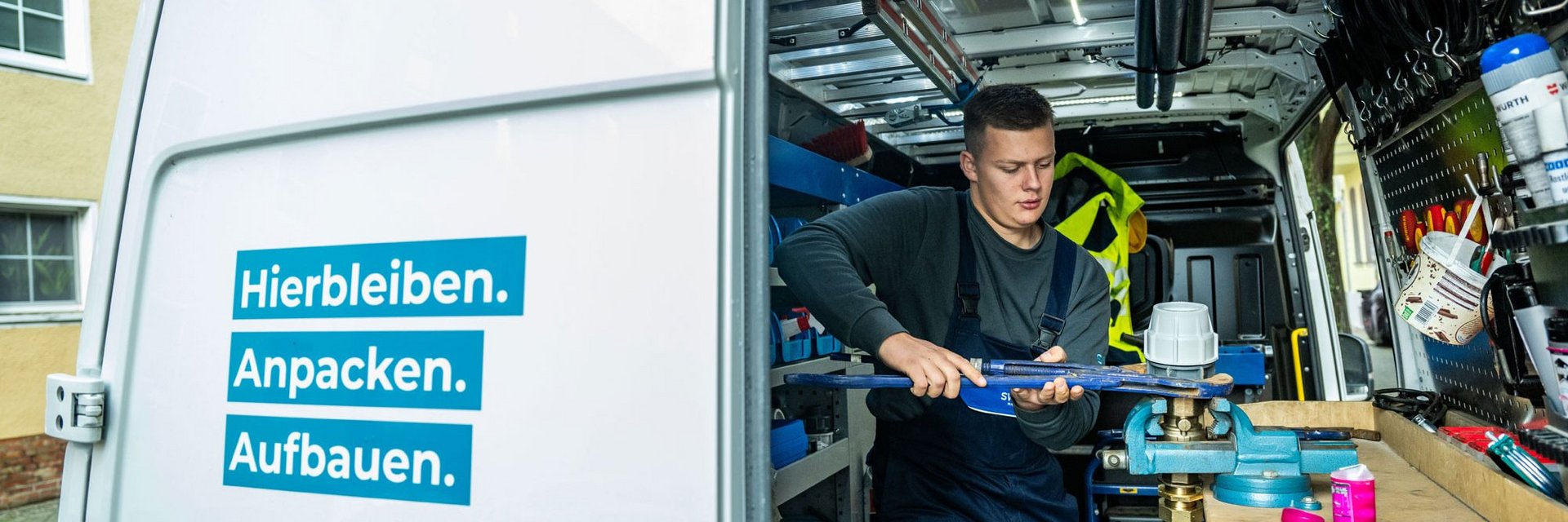 Azubi Anlagenmechaniker steht im SWM Firmenfahrzeug und arbeitet