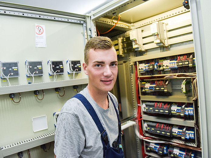 Auszubildener zum Eletroniker für Betriebtechnik steht vor Schaltschrank