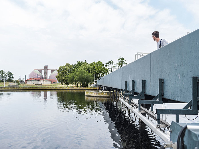 Azubi Fachkraft für Abwassertechnik im Klärwerk Azubi Fachkraft für Abwassertechnik im Klärwerk guckt zu den Faultürmen
