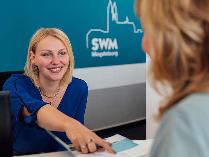 Eine SWM Mitarbeiterin berät eine Kundin am Empfang im SWM Kundencenter