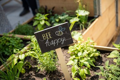 Schild "bee happy" in Nachbars Garten