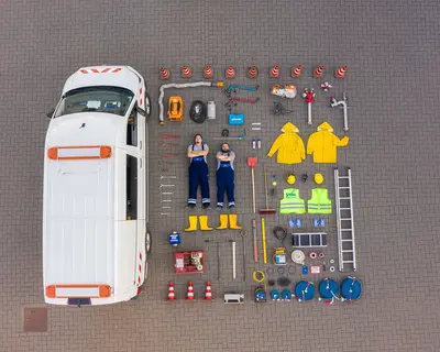 Mitarbeiter aus dem technischen Bereich liegen nach dem Tetrisvorbild inkl. allem, was im Firmenwagen liegt, nebem dem Auto.
