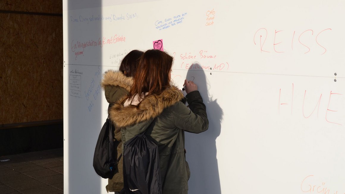 Zwei Frauen schreiben etwas auf weißes Plakat am alten Blauen Bock