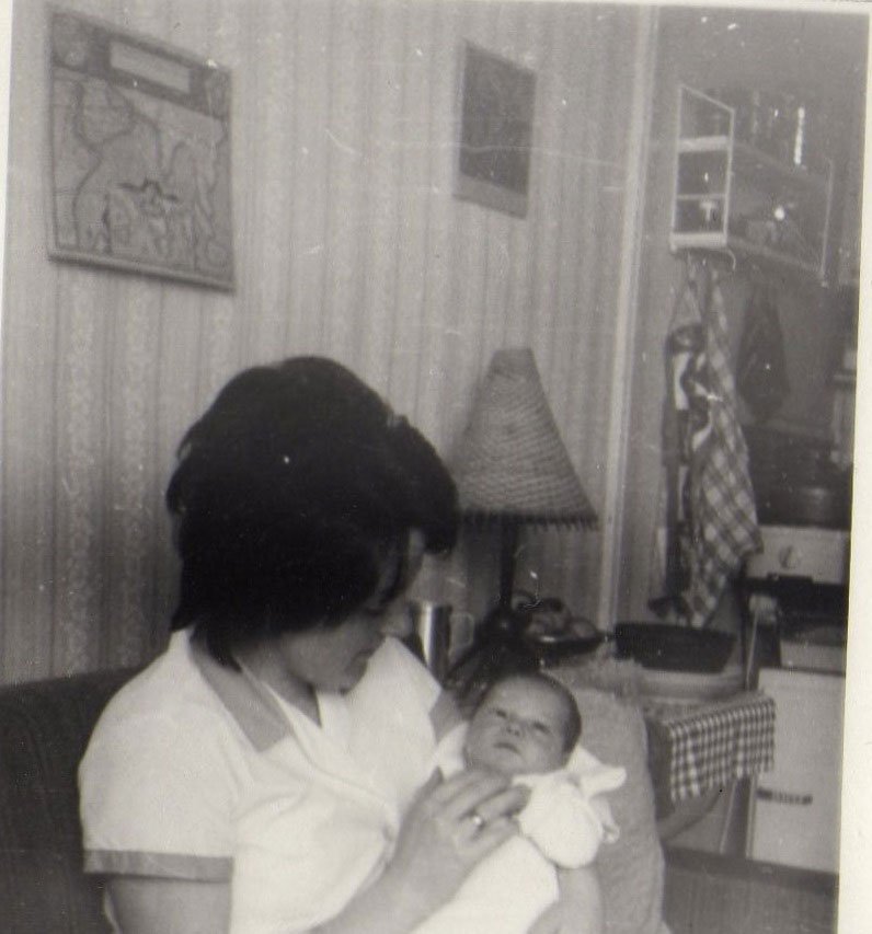 Frau mit Baby im Arm sitzt in Wohnung im alten Blauen Bock