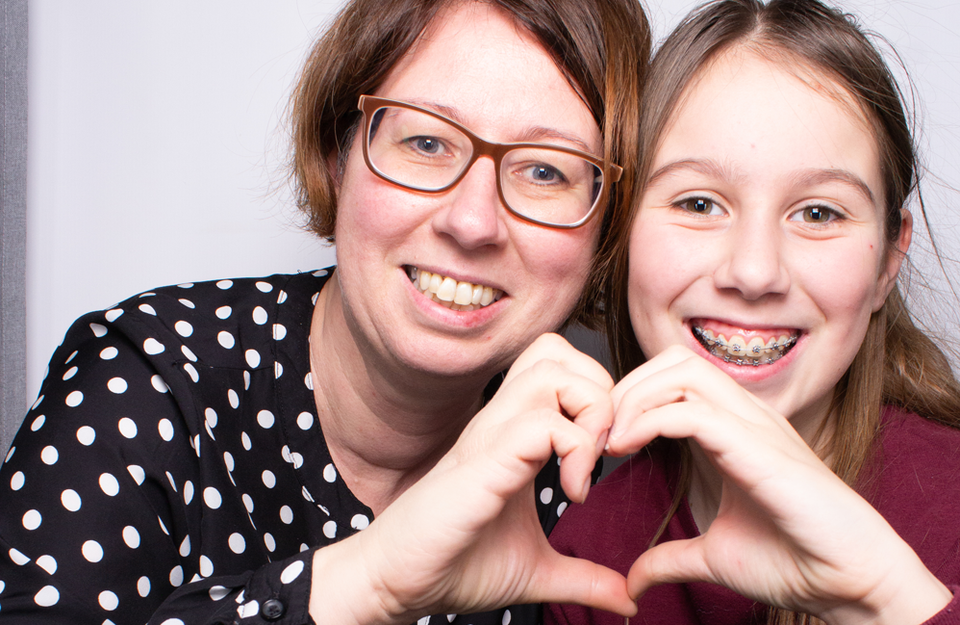 Mutter und Tochter SWM Mitarbeiterin mit Tochter formen mit ihren Händen zusammen ein Herz