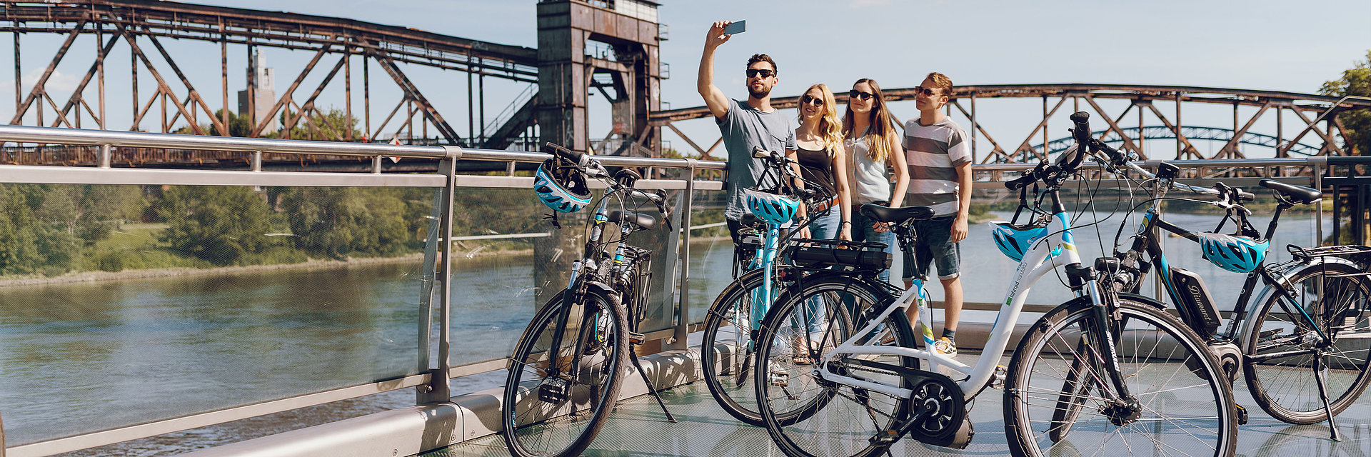 Eine Gruppe fotografiert sich auf einer SWM E-Bike-Tour vor der Hubbrücke in Magdeburg an der Elbe.