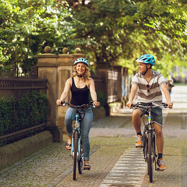 Eine Frau und ein Mann fahren im Sommer mit einem E-Bike durch die Hegelstraße in Magdeburg. 