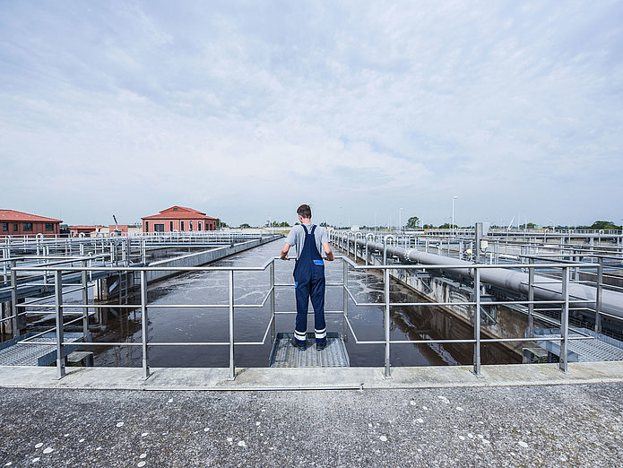 SWM Azubi Fachkraft für Abwassertechnik im Klärwerk SWM Azubi Fachkraft für Abwassertechnik im Klärwerk guckt im Außenbereich auf die Klärbecken