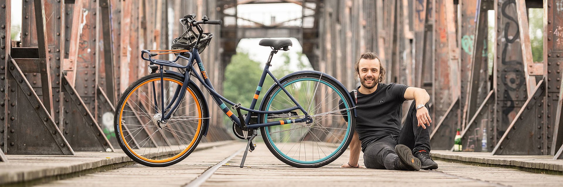 junger Mann sitzt neben trittfest Rad mike auf der Hubbrücke