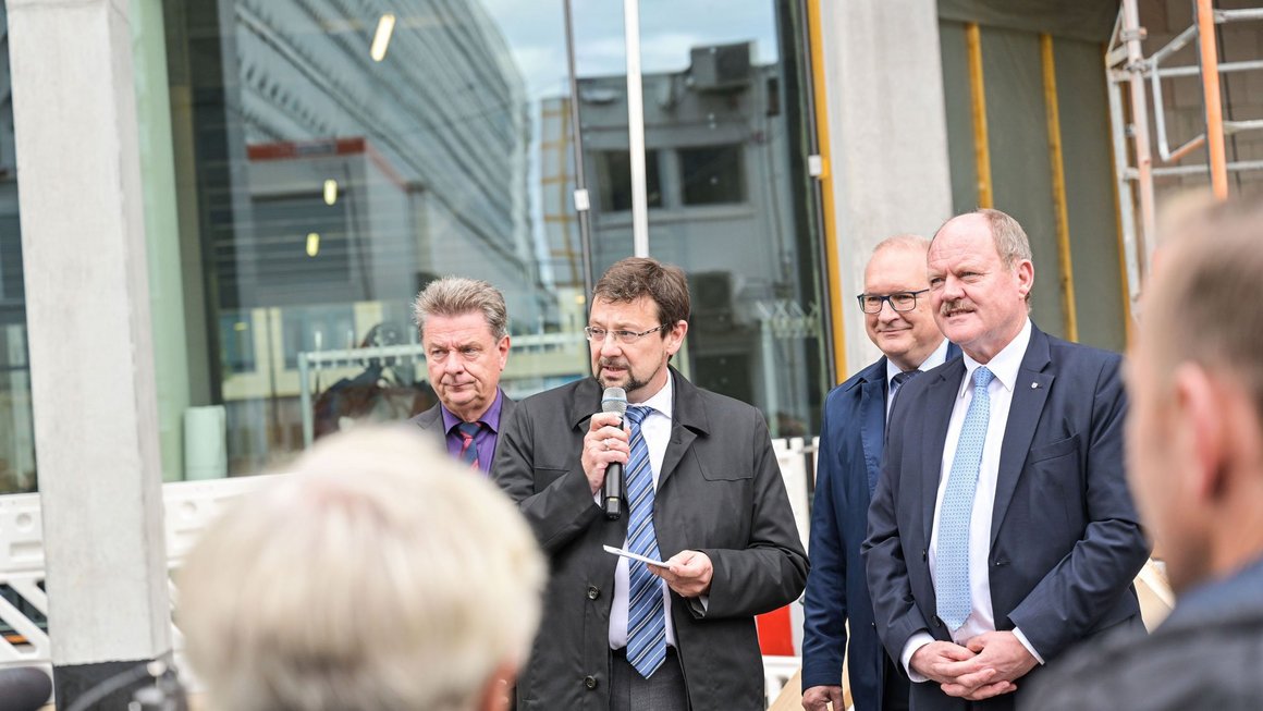 Männer in Anzügen halten Rede zum Richtfest 