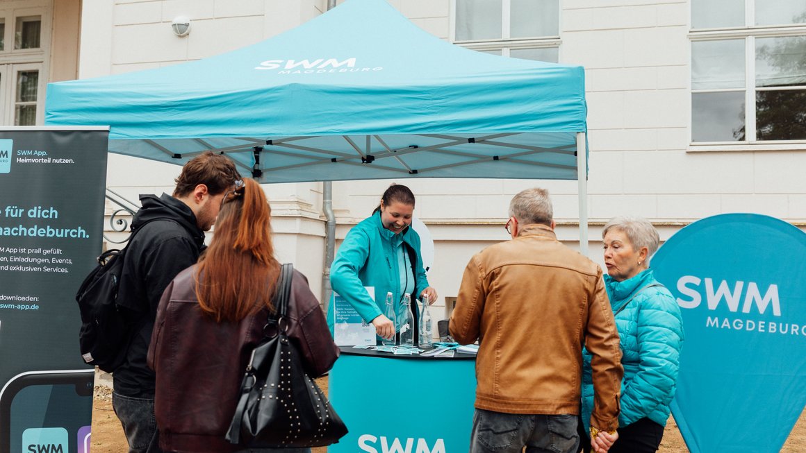 Besucher unterhalten sich mit Mitarbeiterin am SWM Stand