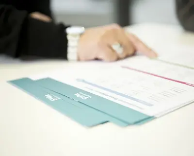 Eine Frau zeigt auf eine Position in SWM Verträgen, die auf dem Tisch liegen.