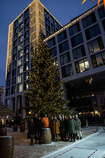 Gruppe von Menschen vor dem Weihnachtsbaum auf dem SWM Weihnachtsmarkt