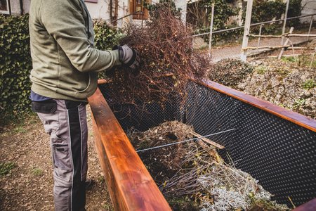 Mann befüllt Hochbeet mit Ästen und Zweigen