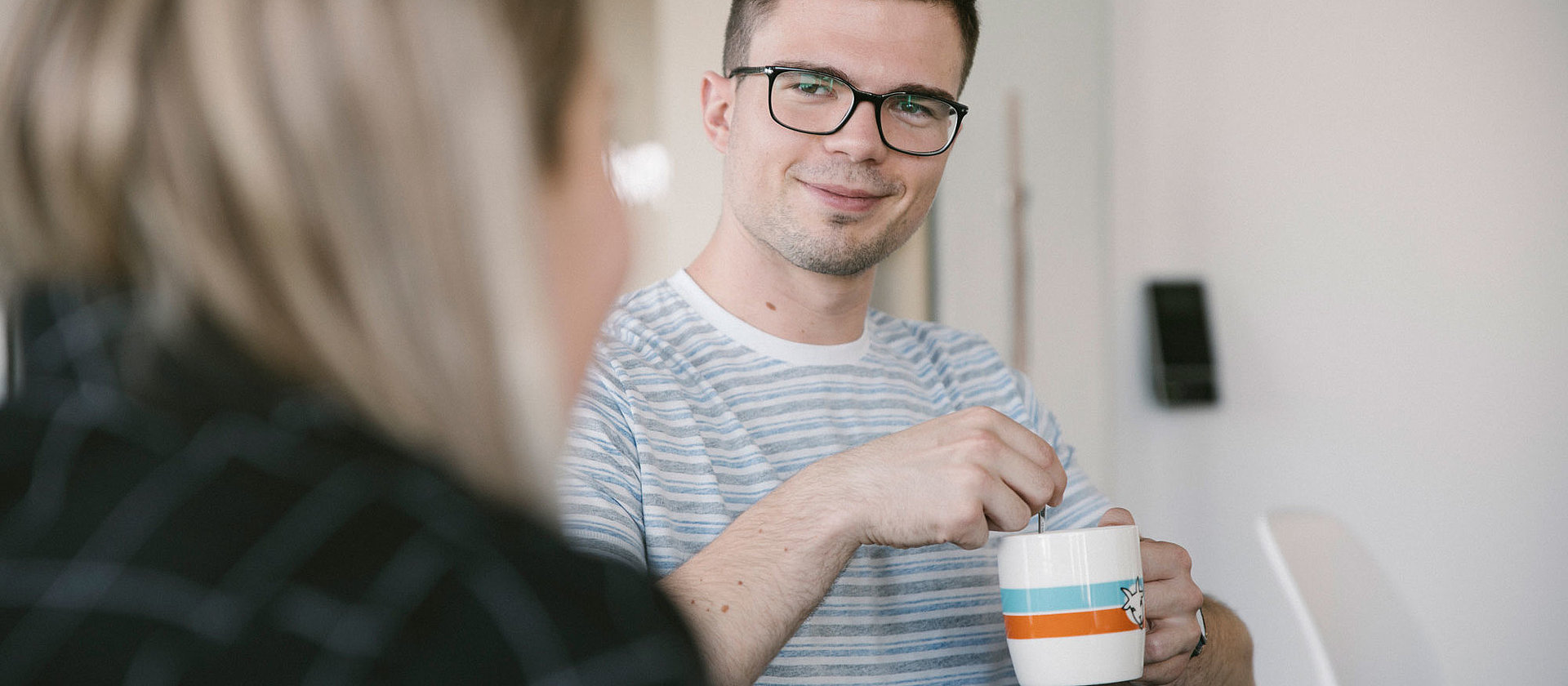 Ein Auszubildender hält eine Tasse und lächelt