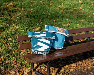 zwei SWM Fahrradtaschen aus recylcelten Werbebannern stehen auf einer Bank