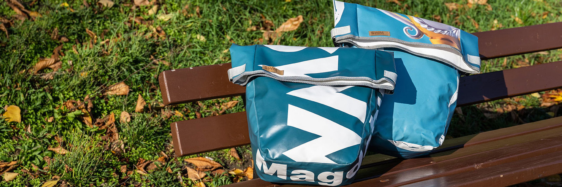 zwei SWM Fahrradtaschen aus recylcelten Werbebannern stehen auf einer Bank