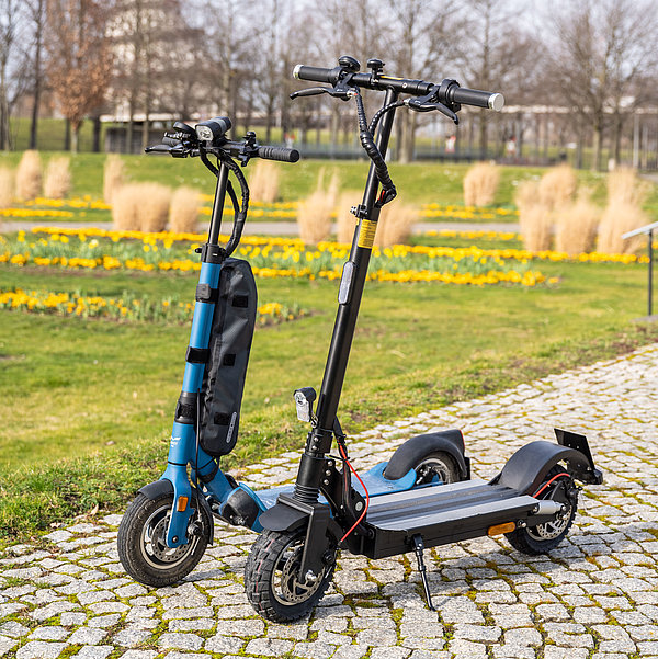 Zwei SWM E-Scooter stehen im Elbauenpark. Im Hintergrund ist der Jahrtausendturm zu sehen.