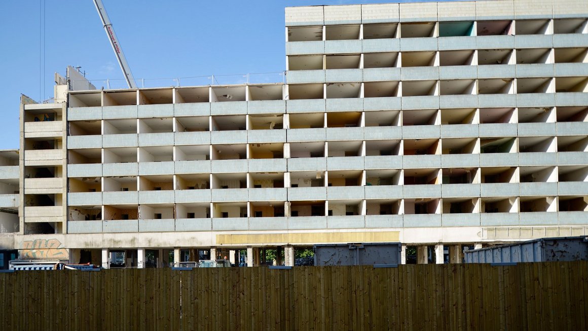 Alter Blauer Bock während des Abrisses mit Baukran und Bauzaun im Vordergrund