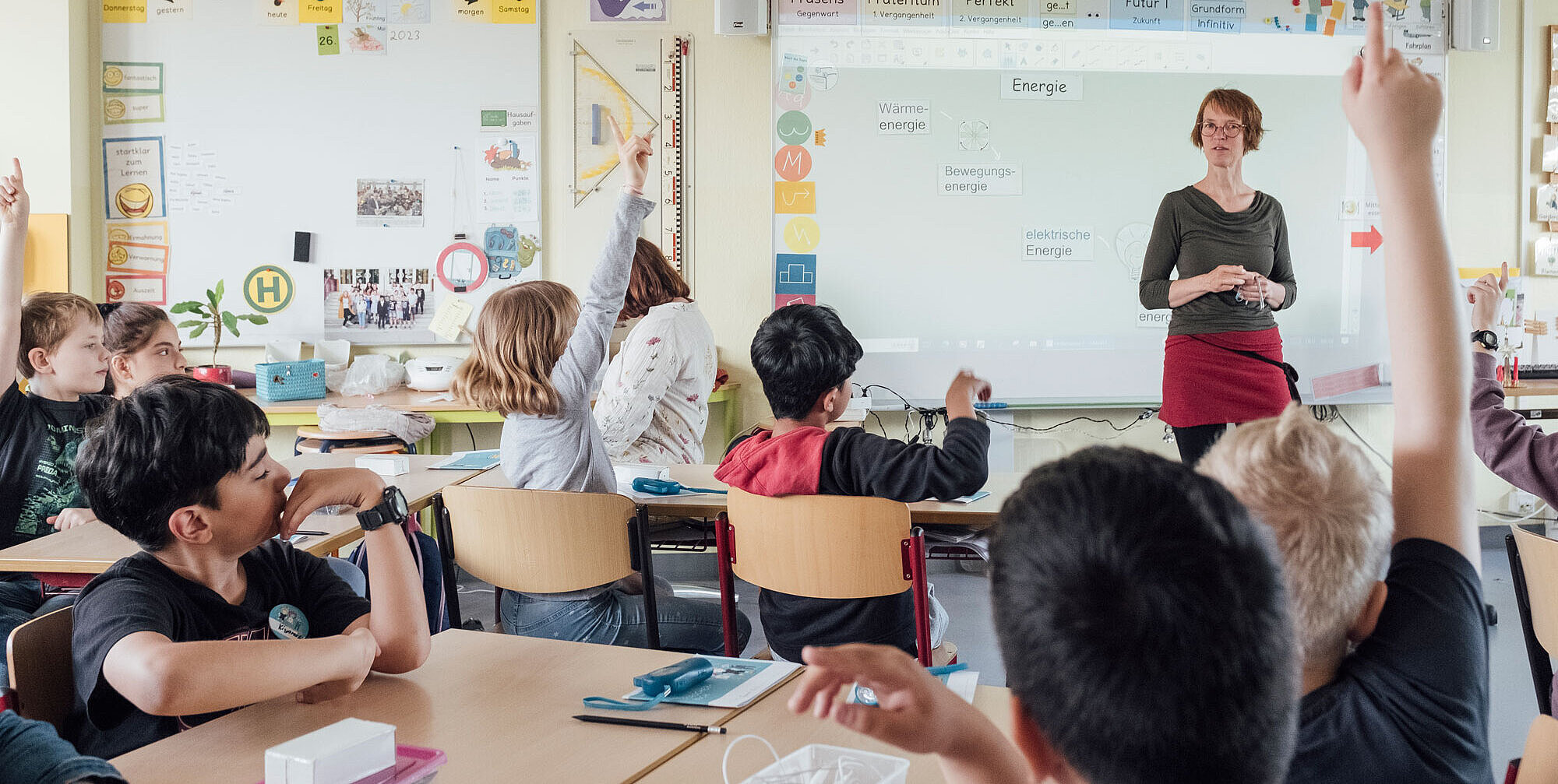 BlitzKitz-Lehrerin steht vor einer Klasse und Schüler:innen melden sich