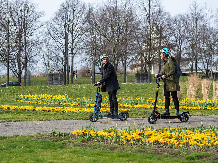 E-Scooter Ausflug durch den Elbauenpark Ein Mann und eine Frau fahren auf dem E-Scooter im Frühling durch den Elbauenpark in Magdeburg.