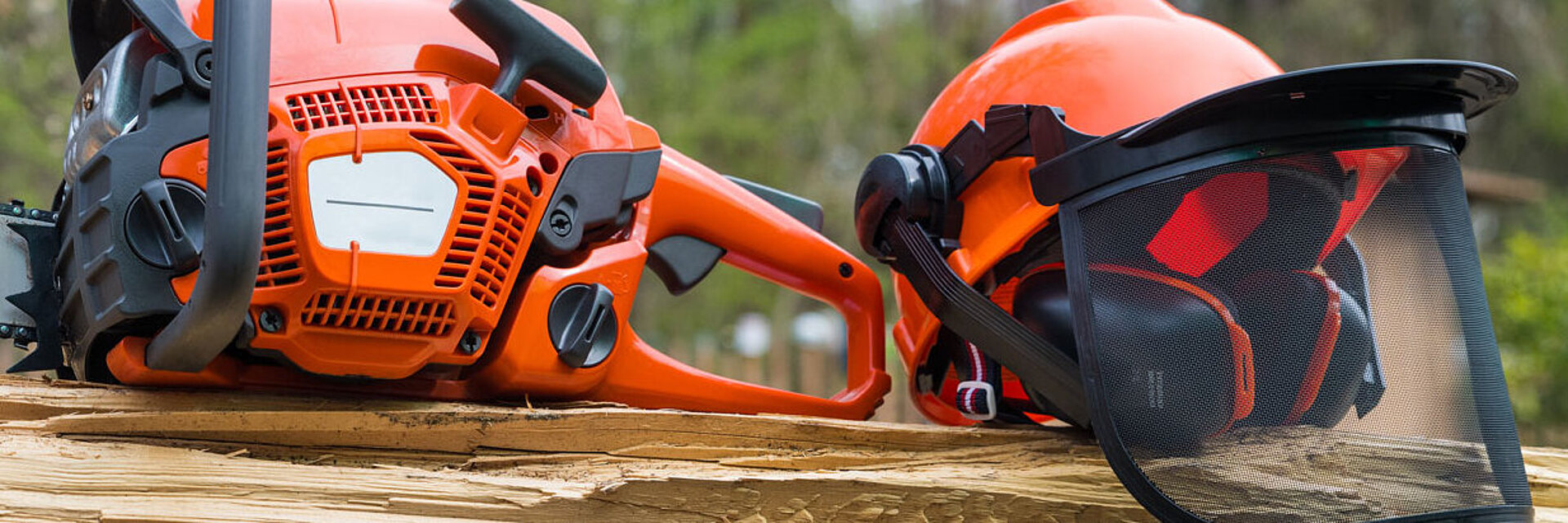 Motorsäge und Helm liegen auf einem Holzstamm