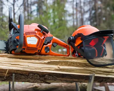 Motorsäge und Helm liegen auf einem Holzstamm