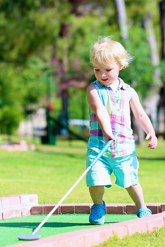 Kleines Kind spielt Minigolf