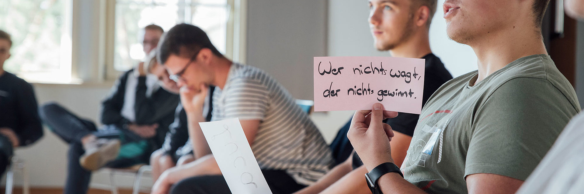 Azubi hält ein Schild hoch mit der Aufschrift „Wer nicht wagt, der nicht gewinnt“