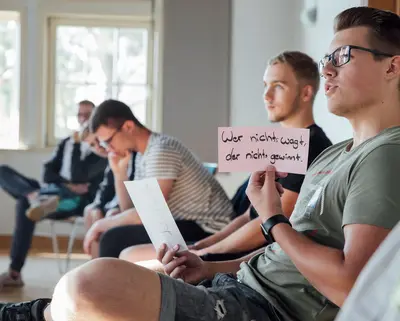 Azubi hält ein Schild hoch mit der Aufschrift „Wer nicht wagt, der nicht gewinnt“