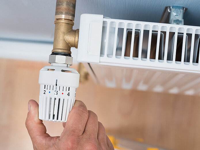 Jemand dreht an einem Heizungsthermostat