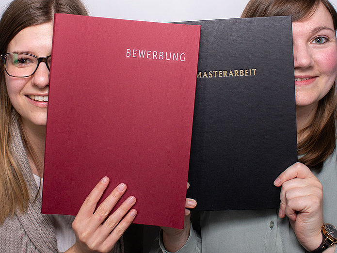 Bewerbung und Masterarbeit bei SWM Zwei Mitarbeiterinnen von SWM zeigen eine Bewerbung und eine Masterarbeit in die Kamera