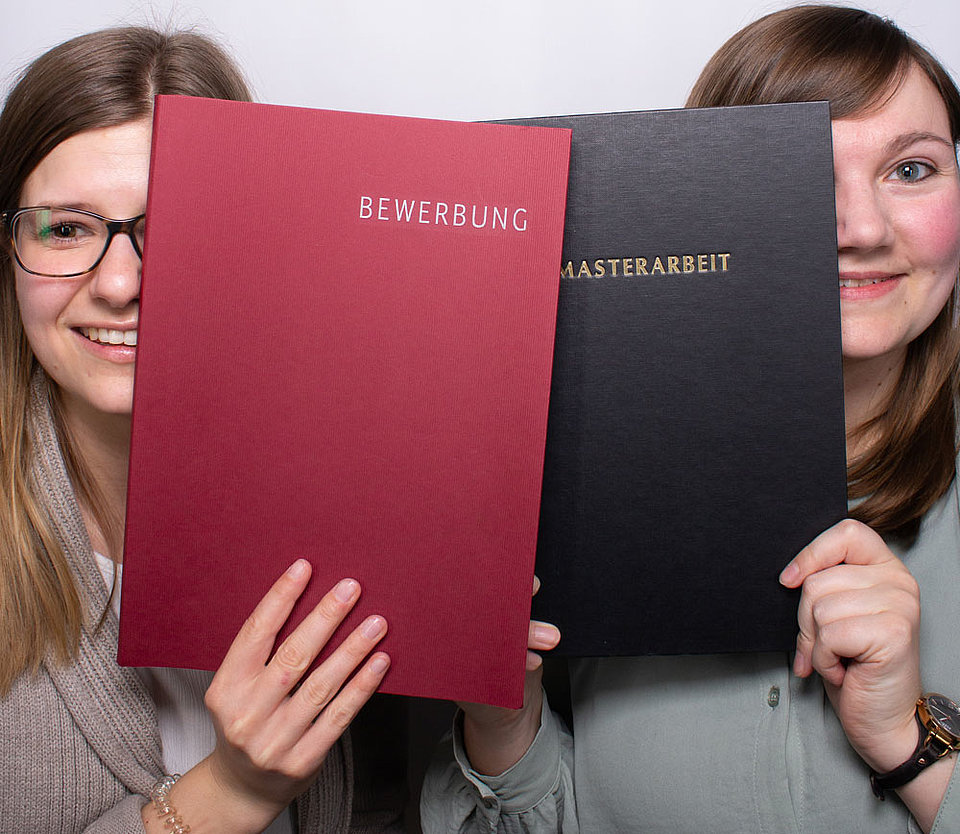 Bewerbung und Masterarbeit bei SWM Zwei Mitarbeiterinnen von SWM zeigen eine Bewerbung und eine Masterarbeit in die Kamera