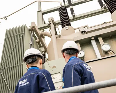 Zwei SWM Mitarbeiter:innen stehen vor technischen Anlage und blicken hoch
