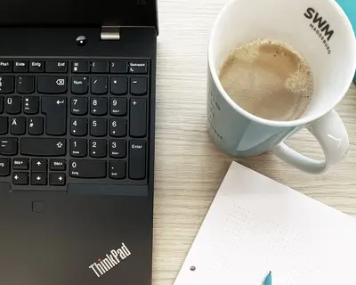 Laptop mit Kaffeetasse und Block
