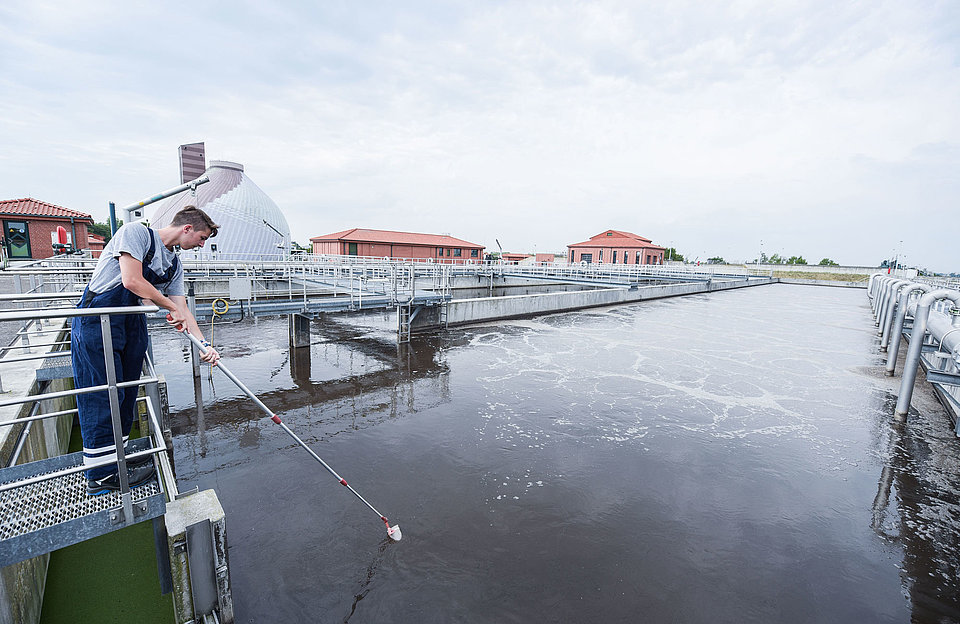 SWM Azubi Fachkraft für Abwassertechnik im Klärwerk keschert in einem Klärbeckener 