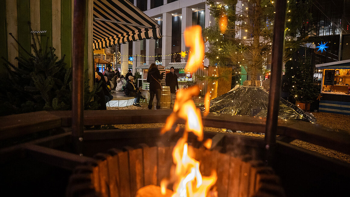 Blick auf den SWM Weihnachtsmarkt mit Feuertonne im Vordergrund