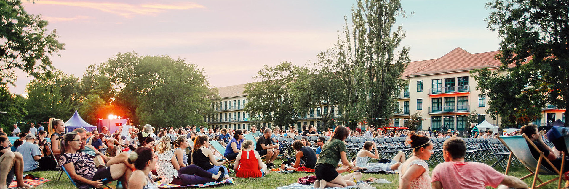 Gäste des SWM Sommerkinos sitzen auf der Wiese auf dem Campus der Hochschule Magdeburg/Stendal