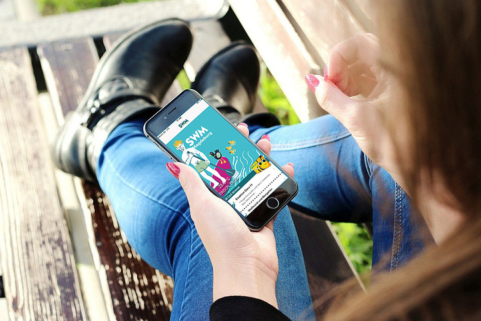 SWM App Startbildschirm Frau sitz mit ihrem Handy auf einer Bank und startet die SWM App