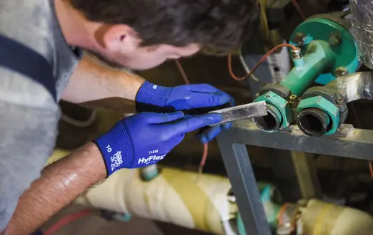Azubi zum Anlagenmechaniker mit Feile in der Hand bei der Arbeit