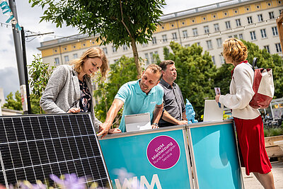 SWM PV-Experte und Energieberater beraten zwei Kundinnen in Nachbars Garten