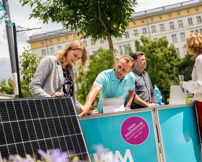 SWM PV-Experte und Energieberater beraten zwei Kundinnen in Nachbars Garten