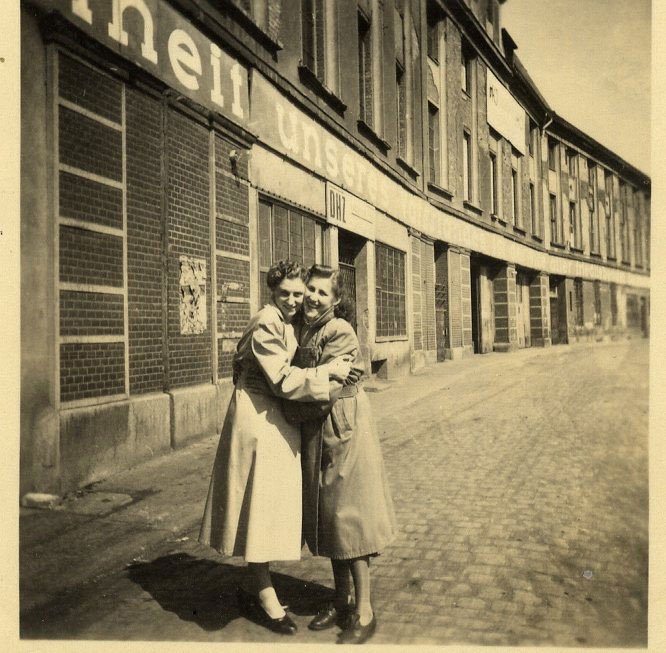 Ein Geschwisterpaar (zwei Frauen) umarmen sich auf der Straße