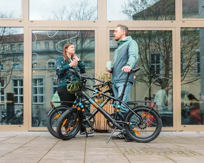 Zwei Radfahrer:innen stehen neben zwei E-Bikes E.mil 