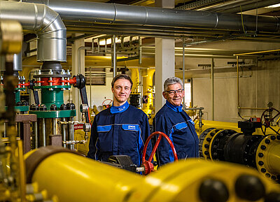 Zwei SWM Mitarbeiter aus dem Bereich Gas stehen in einer Gasdruckregelstation